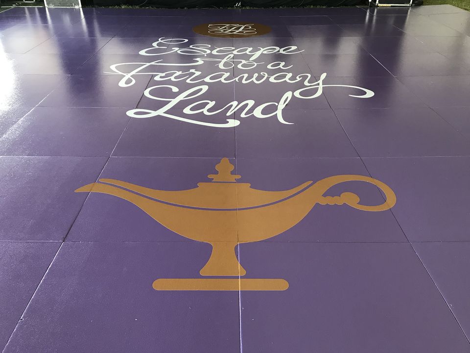 Purple dance floor with a printed gold lamp design and script