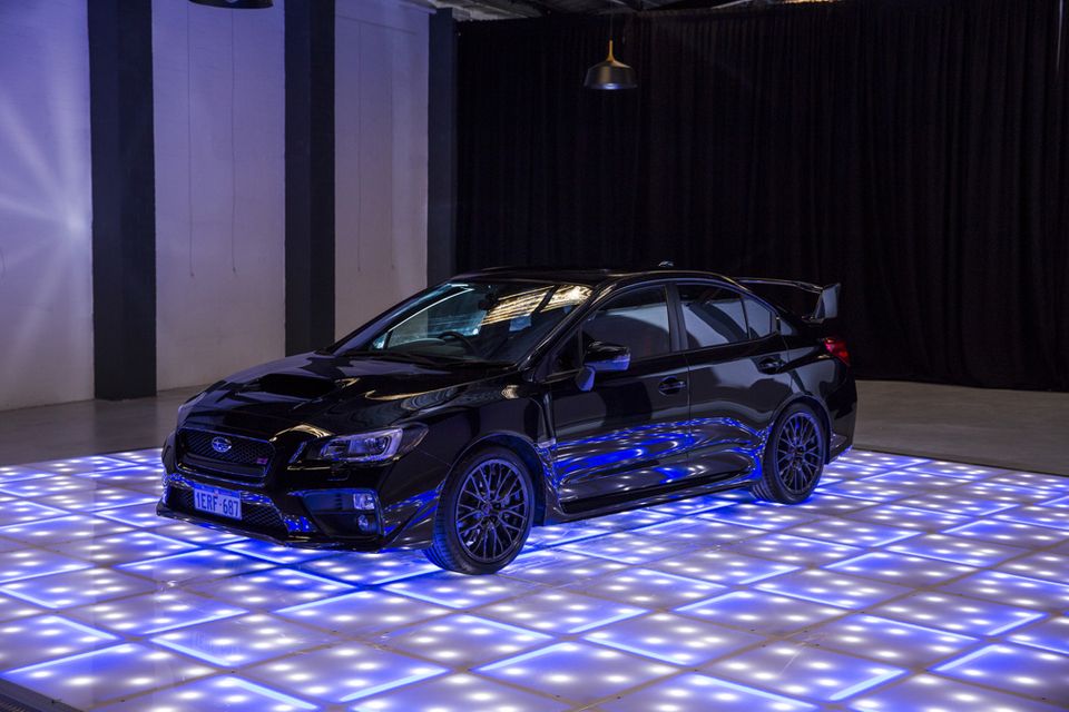 Black sedan displayed on an illuminated LED floor