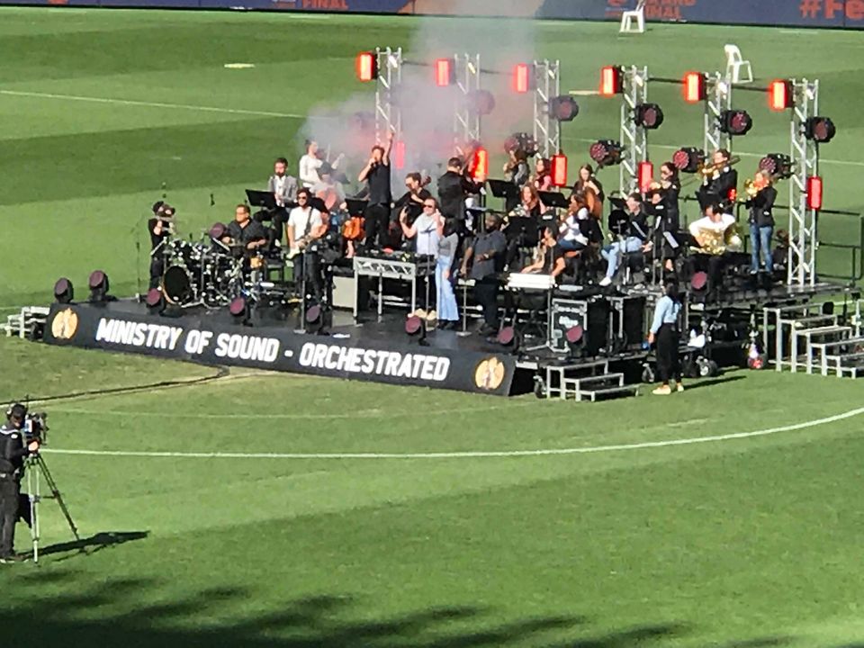 Large stage on a sports field with an orchestra performing
