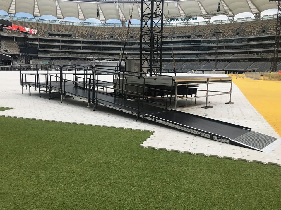 Raised staging decks and ramps set up on a stadium surface