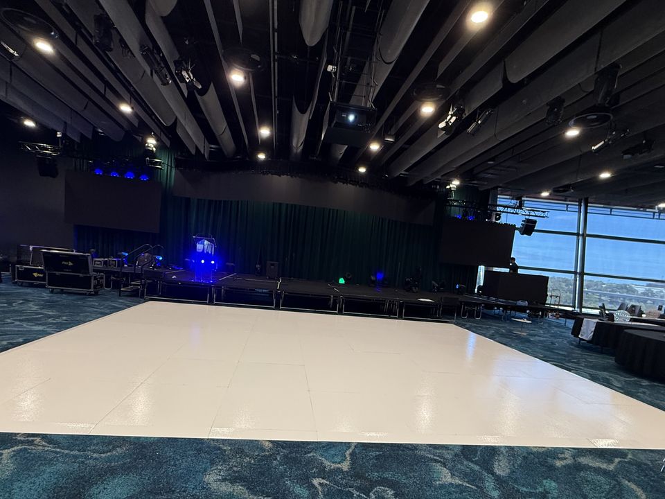 Dance floor laid in a function room, with a stage and lighting rig behind it