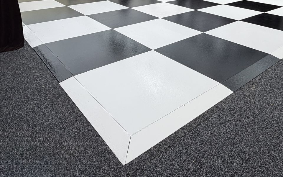 Black and White Check dance floor with white edge trim, laid on carpet inside a marquee