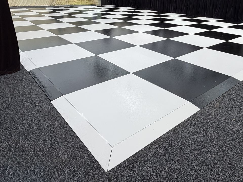 Black and White Check dance floor with white edge trim, laid on carpet inside a marquee