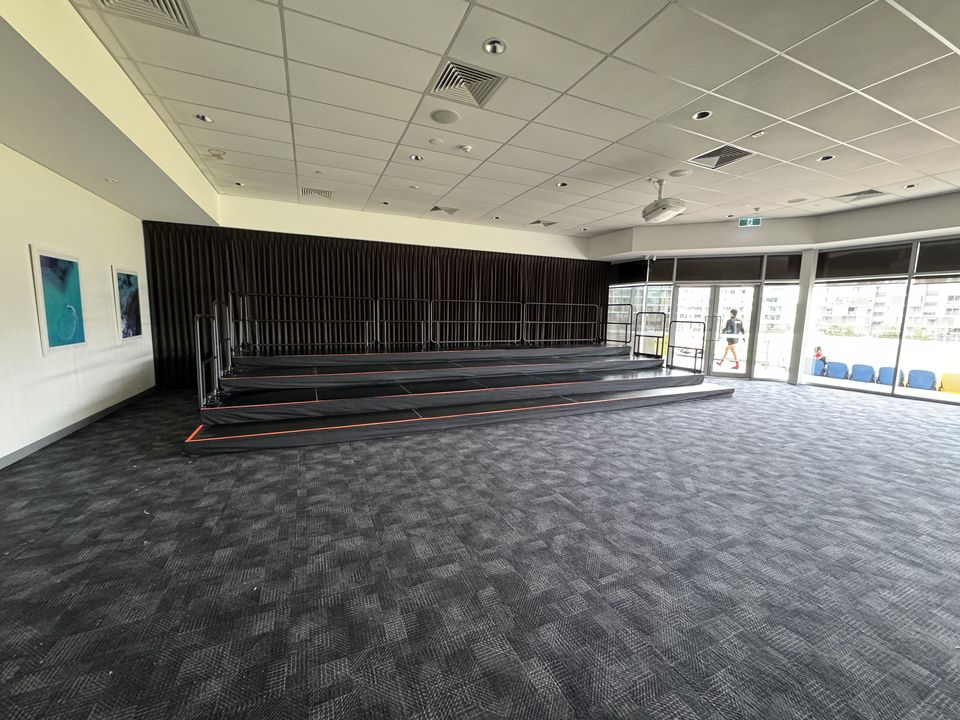 Three-tier black risers with rear handrails in a carpeted function room