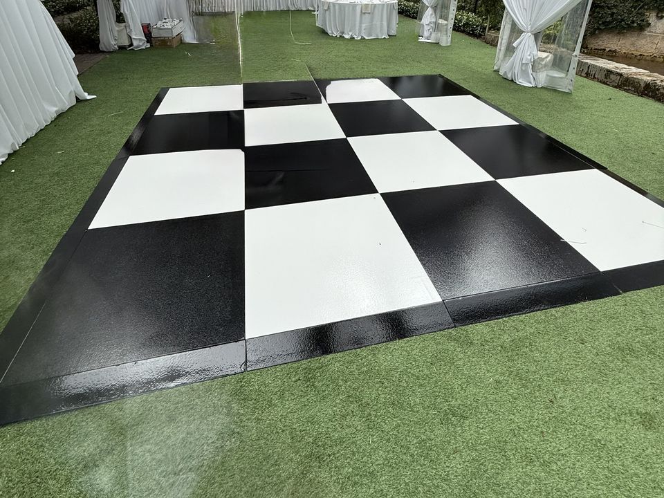 Black and White Check dance floor on turf inside a clear-roof marquee with white drapes