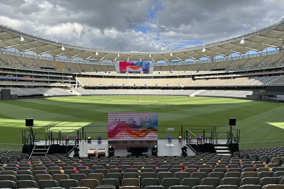 Event stage with stairs and handrails on a stadium field, facing rows of seating