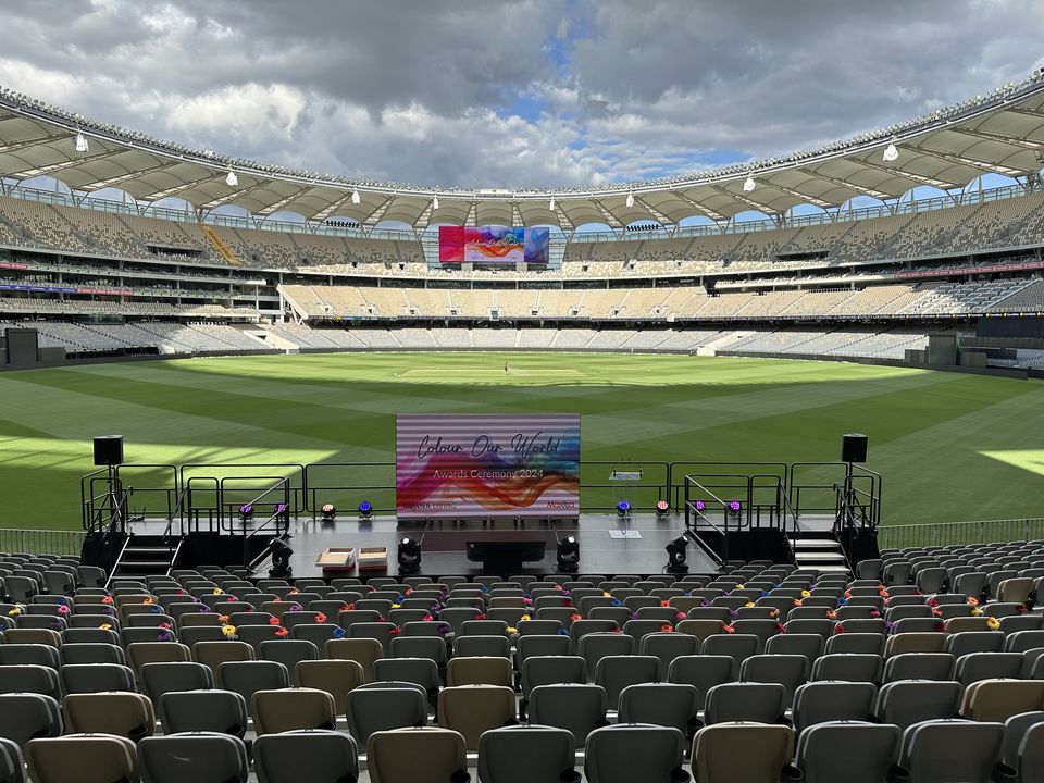 Event stage with stairs and handrails on a stadium field, facing rows of seating