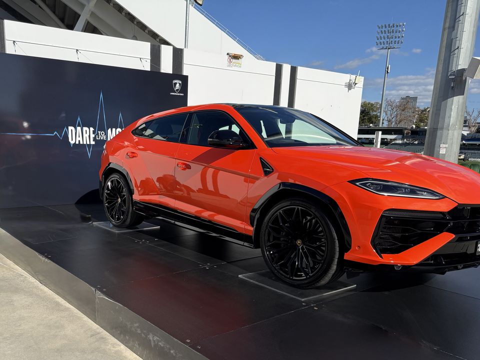 Orange SUV on a black display platform in front of a branded backdrop