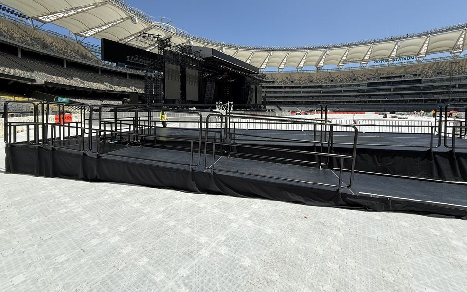 Railed viewing platform with an accessibility ramp on a stadium surface