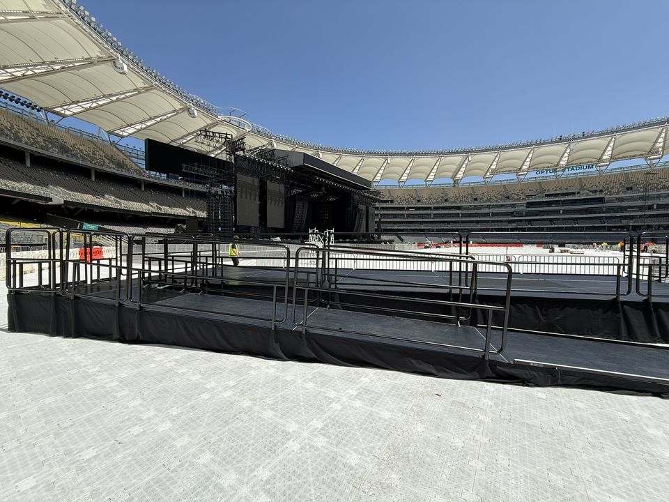 Railed viewing platform with an accessibility ramp on a stadium surface