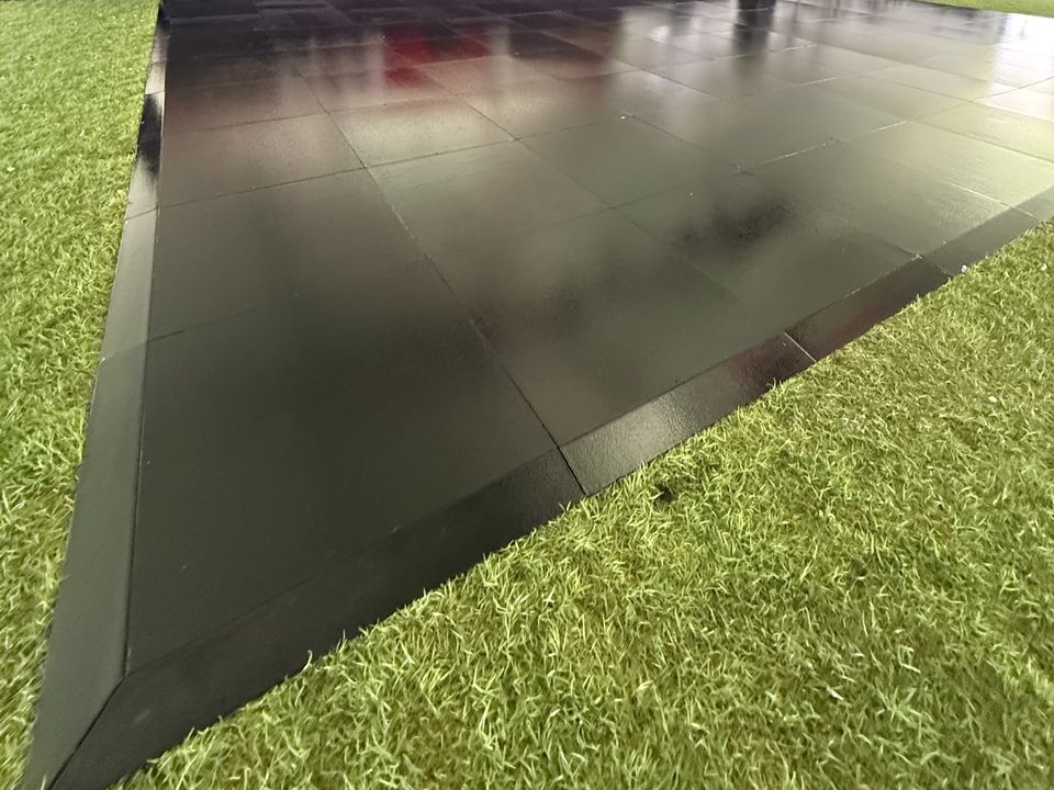 Black gloss dance floor laid on turf inside a marquee