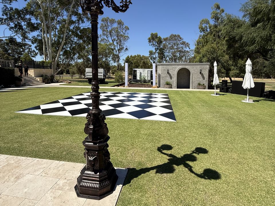 Black and white diamond-pattern dance floor on a lawn beside an ornate lamp post